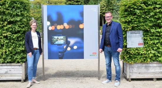 Diana Rolfes (Leiterin Veranstaltungsmanagement Park der Gärten) und Bastian Freese (Projektmanager Fotokultur-Marketing CEWE) neben dem Gewinnerbild 2020 „Doppelbelichtung“ von Peter Bösken, © Park der Gärten 